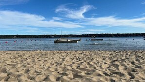 A sandy beach with a clear blue sky and calm water. - Coastal home in Brewster near beaches and bike path RPMS161 (Brewtser)