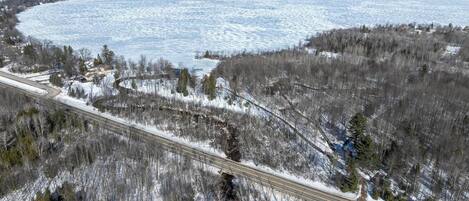 Un paysage hivernal avec un lac gelé, une autoroute et une forêt clairsemée.