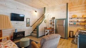 Een gezellig chaletinterieur met houten details, een trap, een eethoek en een keuken.