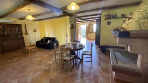 A dining area with a round table set for four, surrounded by wooden chairs. There is a black sofa against a yellow wall, and a wooden cabinet with glass doors is visible in the background. - Sardinia Re - Country Villa Pala Venalza Loft (Olmedo)