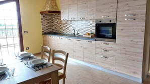 A modern kitchen with light wood cabinetry, a tiled backsplash, and stainless steel appliances. - Sardinia Re - Country Villa Pala Venalza Mansarda (Olmedo)