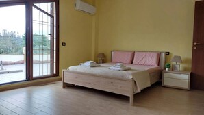 A bedroom with a bed, two bedside tables, a window, and an air conditioning unit. - Sardinia Re - Country Villa Pala Venalza Mansarda (Olmedo)