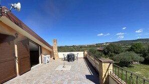 Une terrasse avec une table et des chaises, une cheminée et une vue sur la campagne.