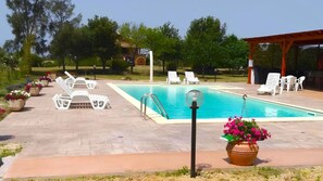 Une piscine avec des chaises longues et des plantes en pot.
