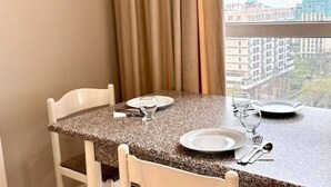 Taula de dinar preparada per a dues persones amb vista a edificis a través d'una finestra.
