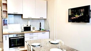 Una cuina moderna amb armaris blancs, un microones, un forn i una taula de dinar preparada per a dues persones.