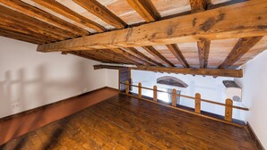 A room with exposed wooden beams, a wooden floor, and a view of a brick structure outside. - Yellow Home by MMega (Florence)