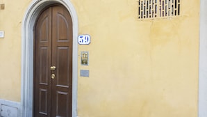 A brown double door with a brass handle, a number 59 sign, and a small plaque on a yellow wall. - Yellow Home by MMega (Florence)