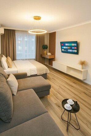 Une chambre d’hôtel moderne équipée d’un lit, d’un canapé, d’une télévision et d’une petite table avec des tasses.
