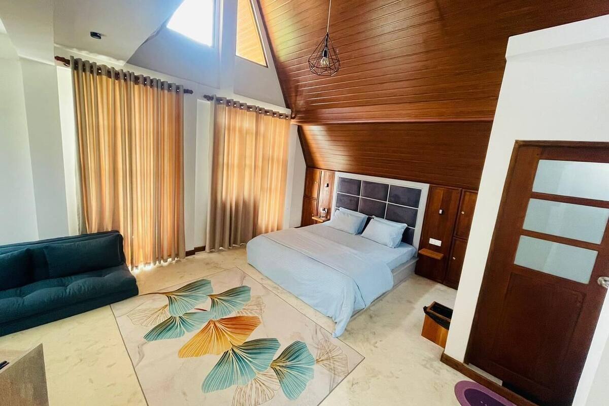 Une chambre à coucher avec un lit, un canapé, un plafond en bois et une fenêtre.