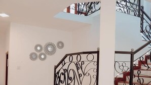 A multi-level interior with a staircase featuring ornate metal railings and a series of circular wall decorations. - Affinity Villa Dikoya (Dick oya)