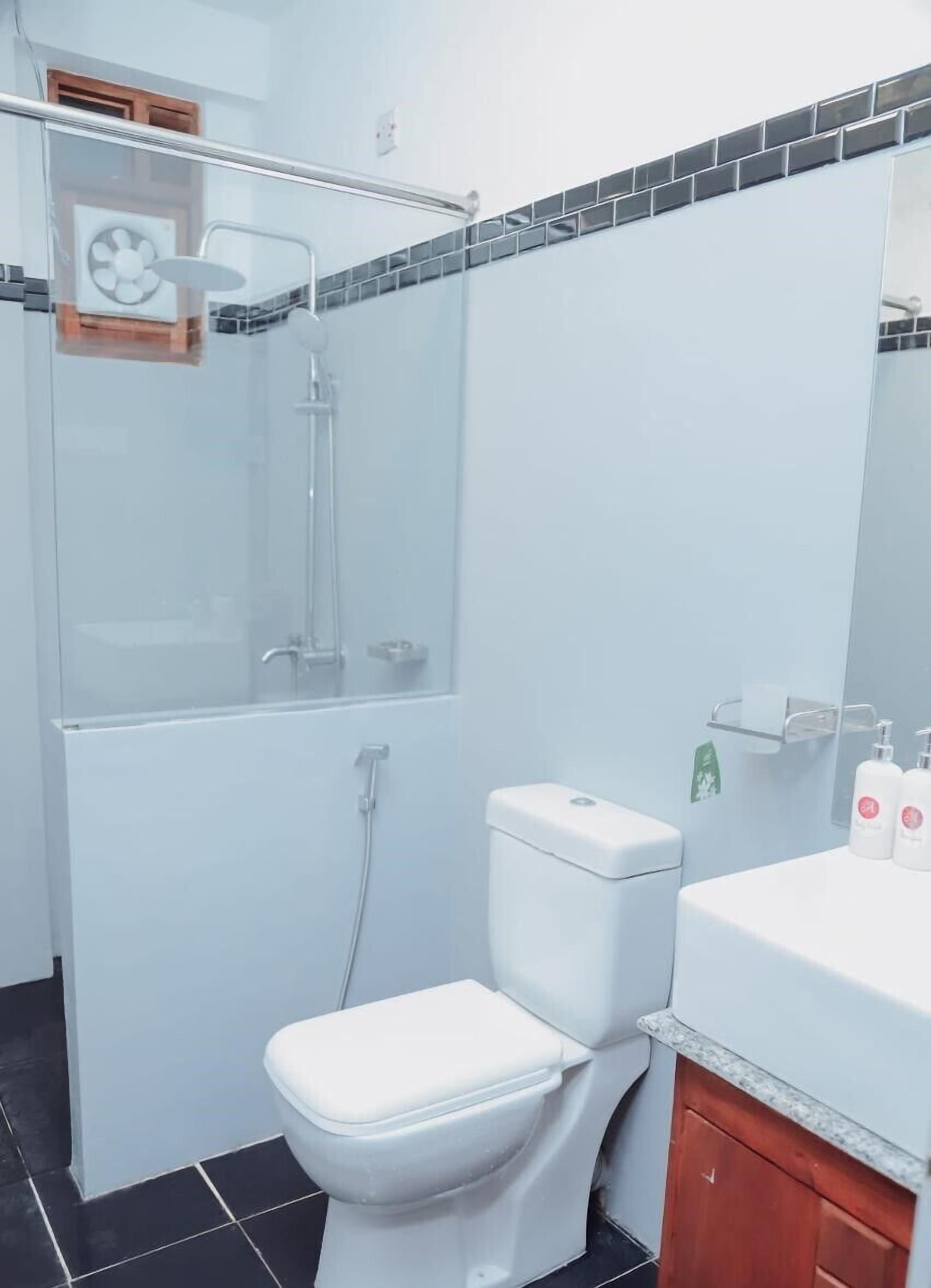 A bathroom with a glass shower enclosure, a white toilet, and a sink with toiletries.