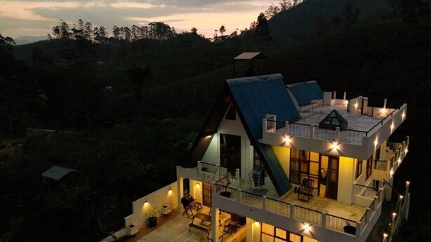 A multi-story house with a balcony, large windows, and a well-lit interior. - Affinity Villa Dikoya (Dick oya)