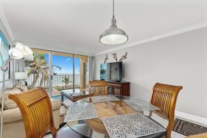 Relax in this stylish living area with a glass-top dining table, flat-screen TV, and comfortable seating.