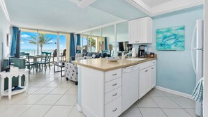 Una cucina moderna con mobili bianchi, un'isola grande e vista sull'oceano.