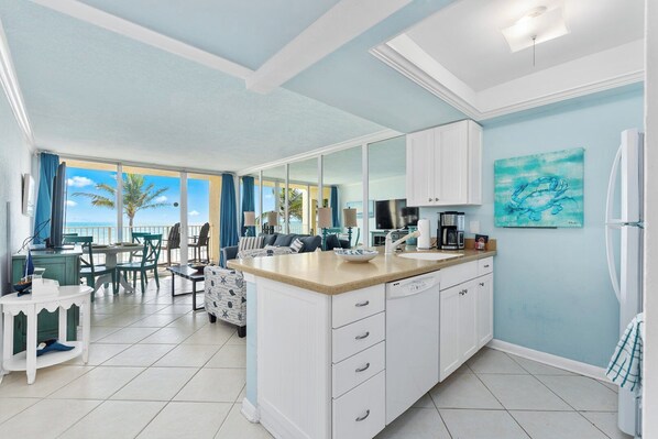 A modern kitchen with white cabinets, a large island, and a view of the ocean.
