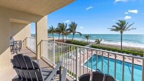 Un balcone con piscina, sedie e vista sulla spiaggia e l'oceano.