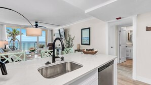 Una cocina moderna con una isla grande, lavavajillas integrado y vistas a la playa.