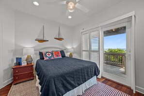 Ein Schlafzimmer mit Bett, Nachttisch, Lampe und Blick ins Freie durch eine Schiebetür.