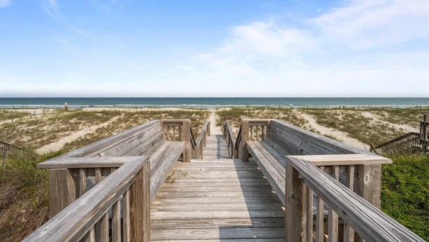 Una pasarela de madera que conduce a una playa con vista despejada al océano.
