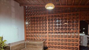 Een wellnessruimte met een houten bank, betegelde vloer en een decoratieve scheiding.