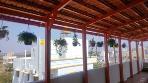 Een overdekt buitengebied met een houten plafond en hangende planten.