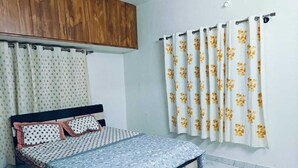 Een slaapkamer met een bed, gordijnen en een houten garderobe.