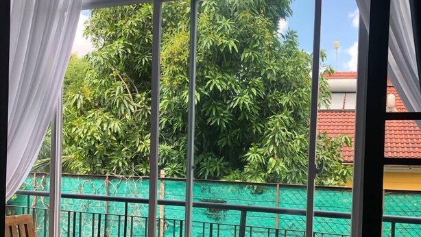 A balcony with a view of a pool and greenery, furnished with a table and chairs. - Bat Chum Villa (Phnom Penh)