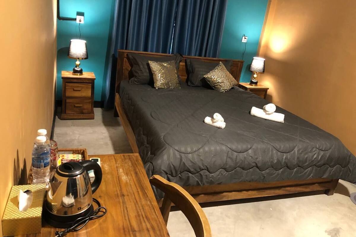 A neatly arranged hotel room with a bed, bedside tables, a wooden desk, and a chair.