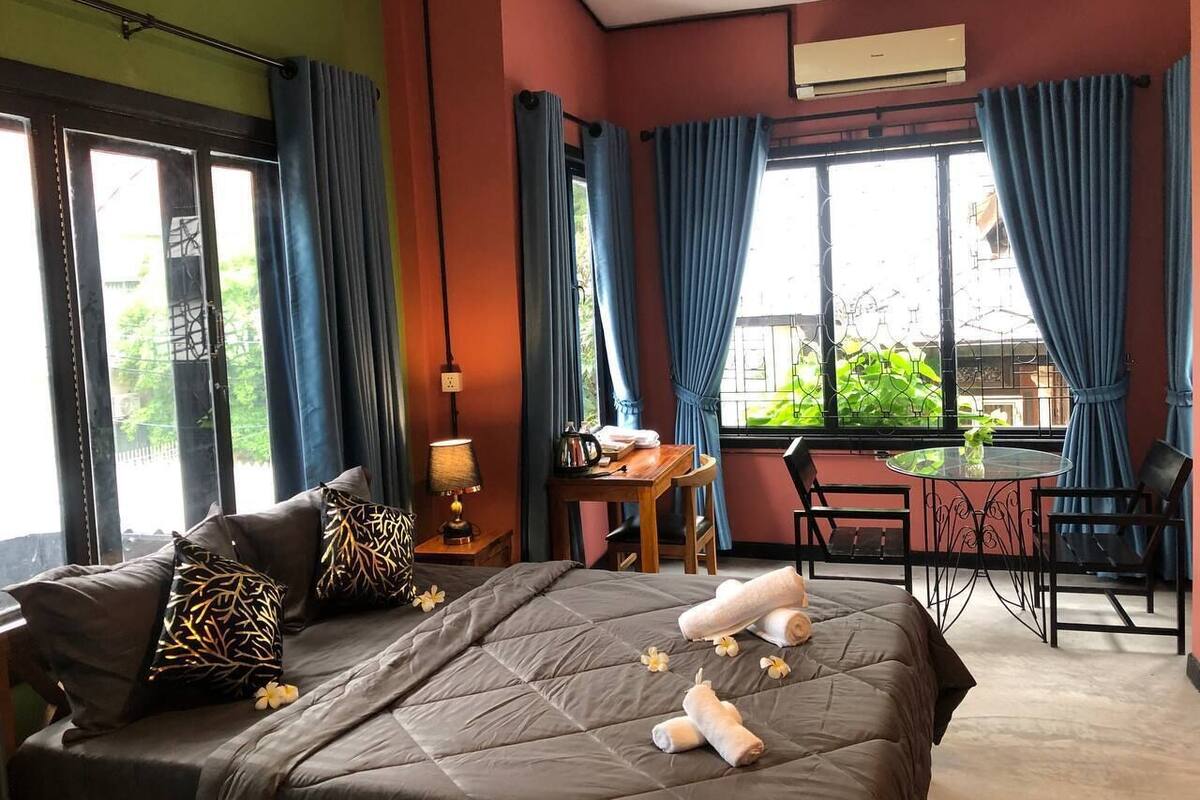 A bedroom with a bed, a desk, a chair, and a dining table.