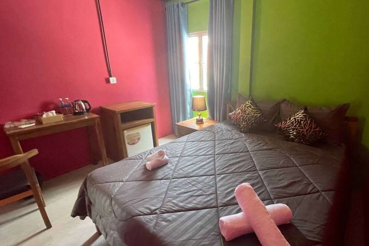 A bedroom with a bed, bedside table, lamp, and a window with curtains.