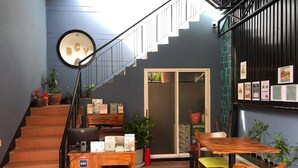 A staircase leading to a door, a wooden desk with a computer, and a table with chairs in a room with tiled flooring. - Bat Chum Villa (Phnom Penh)
