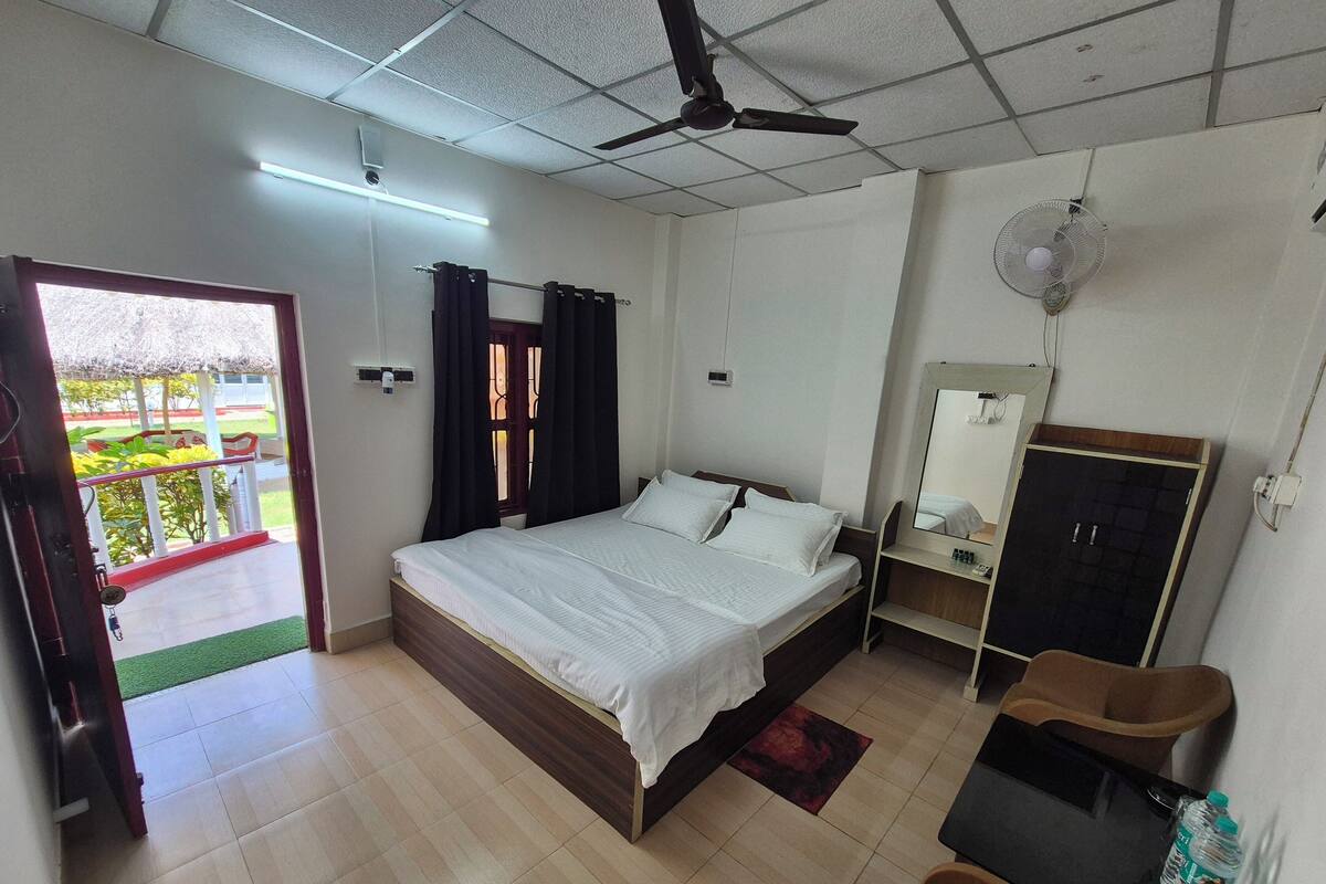 A bedroom with a bed, a desk, a wardrobe, and a balcony with plants.