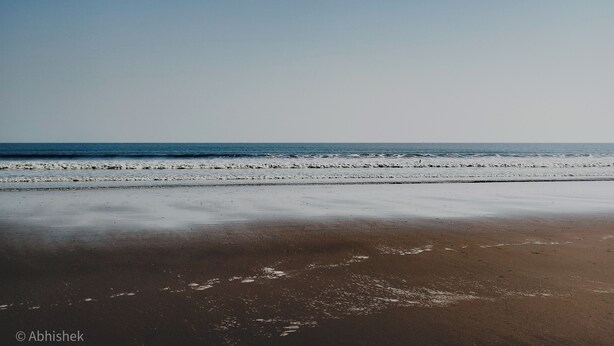Una playa con cielo despejado y mar tranquilo.