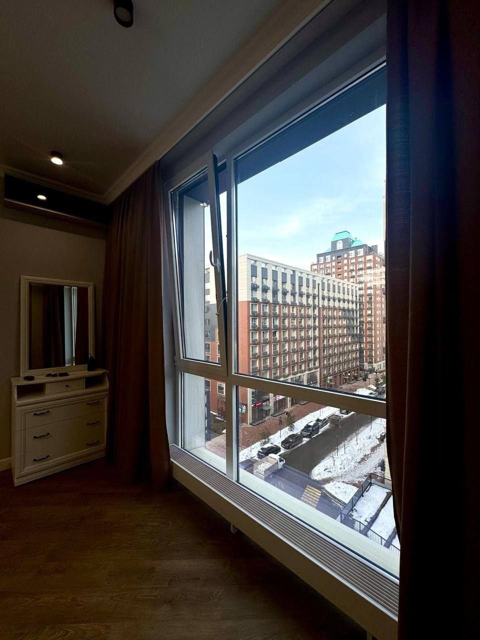 Ein Zimmer mit großem Fenster, einem Schminktisch und einem Spiegel.