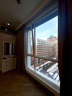 A room with a large window, a dresser, and a mirror.