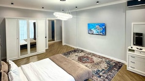 Une chambre à coucher avec un lit, une télévision, une armoire et un miroir.