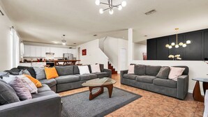 A modern living room with two grey sofas, a glass coffee table, and a staircase leading to a kitchen. - 4736 Family Home Near Disney Sea World (Kissimmee)