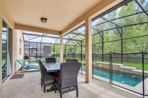 A covered patio with a pool, outdoor furniture, and large windows. - 4736 Family Home Near Disney Sea World (Kissimmee)
