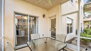 A glass-top table with chairs in an outdoor patio area with sliding glass doors. - Right Direction Rentals 1 Bedroom Villa 9955 (Port St. Lucie)