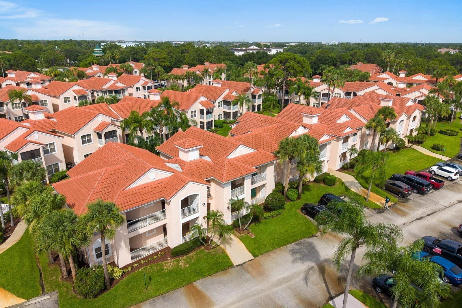 A residential area with multiple two-story buildings, each with a red-tiled roof and surrounded by greenery.