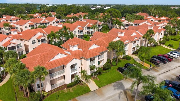A residential area with multiple two-story buildings, each with a red-tiled roof and surrounded by greenery. - Right Direction Rentals 1 Bedroom Villa 9955 (Port St. Lucie)