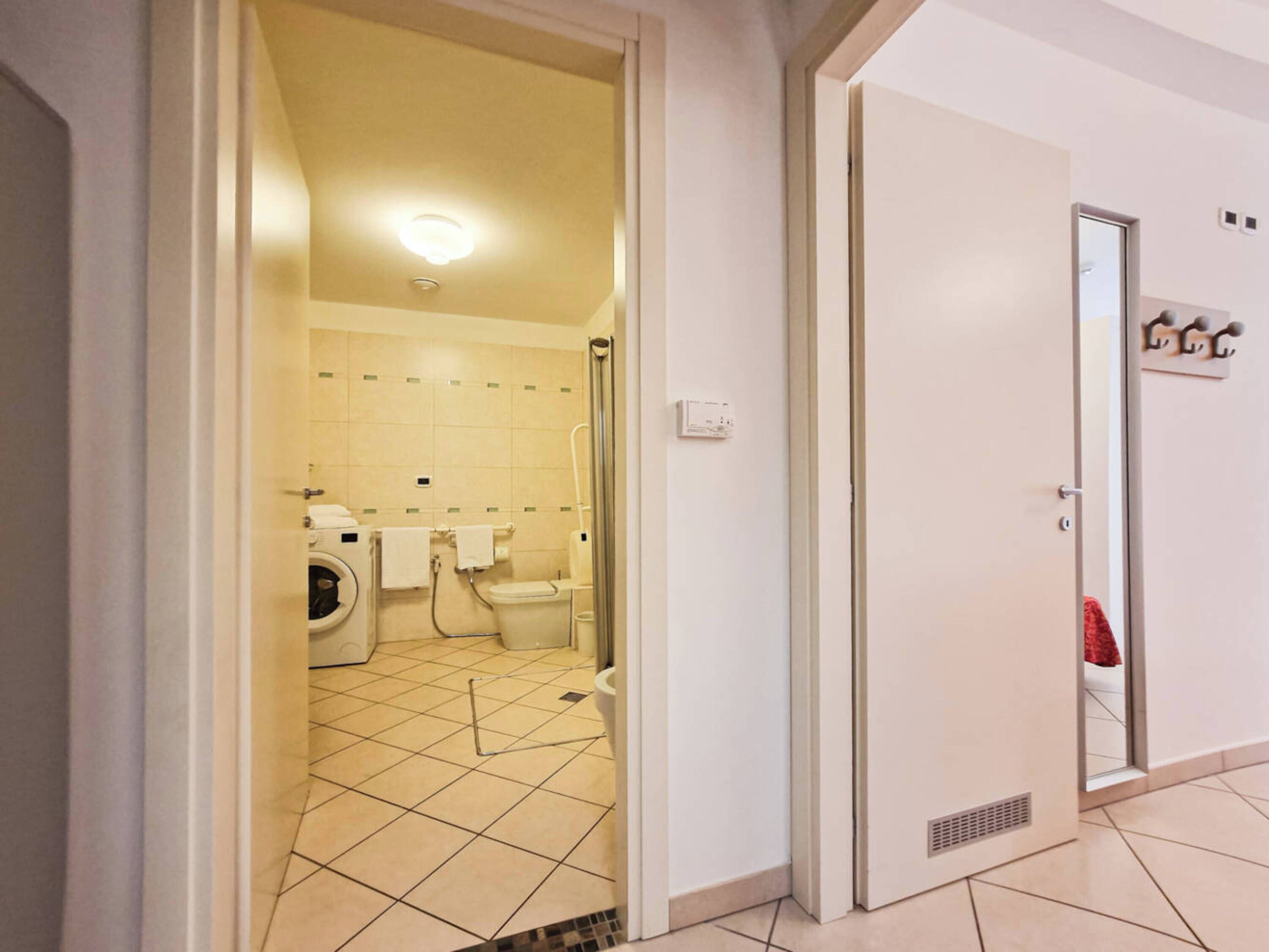 A hotel bathroom with a washing machine, toilet, and shower area.