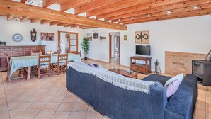 A spacious living area with a wooden ceiling, a dining table with chairs, a sofa, a television, and a fireplace. - Villa Can Paxaco - By Dream Villas Pollensa (Alcudia)
