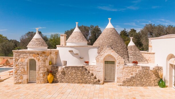 A series of traditional stone buildings with conical roofs, likely part of a historic or cultural site.