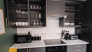 A compact kitchen with dark cabinets, a microwave, a toaster, and a coffee machine. - Chic & Modern Escape (Salford)