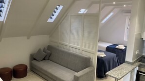 Un dormitorio tipo loft moderno con un sofá gris, una mesita pequeña y una cama con cubrecama azul.