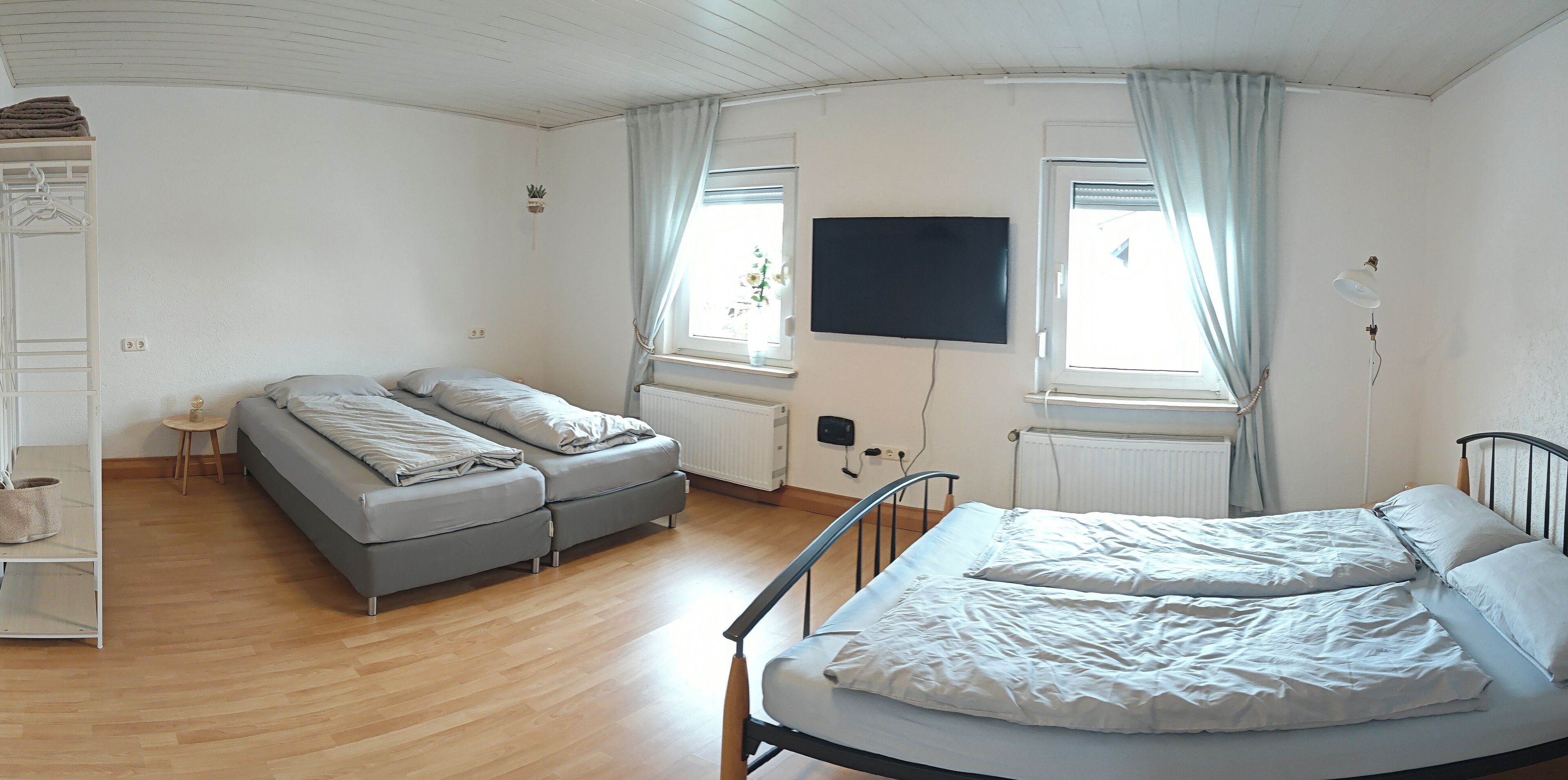 A bedroom with a bed, a sofa, a TV, and a window with curtains.
