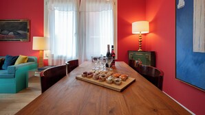 A dining area with a wooden table set for a meal, a sofa, a lamp, and a painting on the wall.