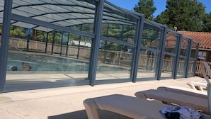 Un espace piscine doté d’une enceinte en verre, de chaises longues et offrant une vue dégagée sur la piscine.